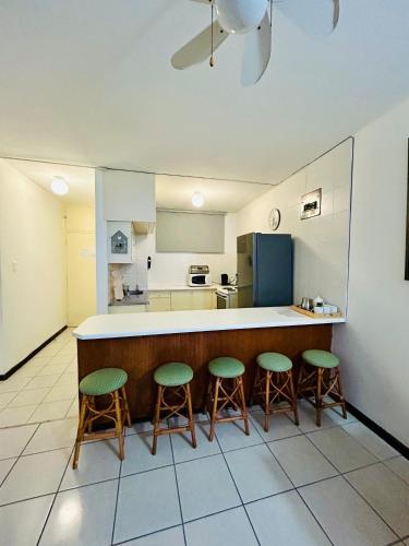 a kitchen with three bar stools and a counter at Coastal Bliss Retreat Peacehaven 207 in Scottburgh