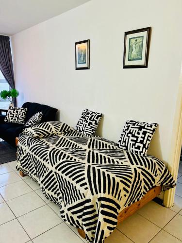 a bed with black and white sheets and pillows at Coastal Bliss Retreat Peacehaven 207 in Scottburgh
