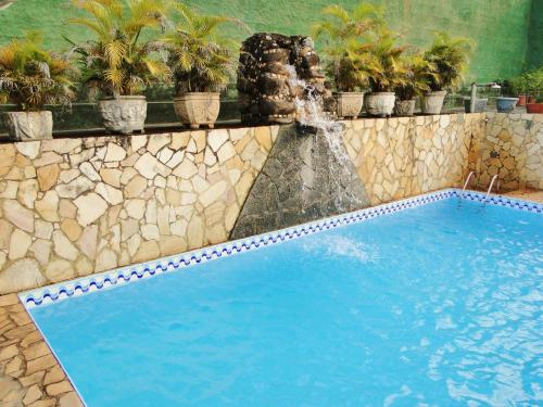 a swimming pool with a fountain and potted plants at Pousada O Meu Canto in Santa Rita de Jacutinga