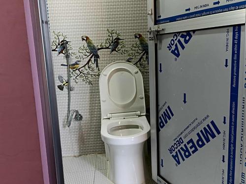 a bathroom with a toilet with birds on the wall at Peace Home Homestay in Nagarkot