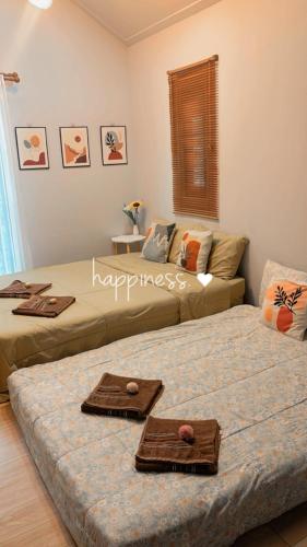 two beds in a room with towels on them at Cana Garden House 1 โฮมสเตย์ in Ban Khok