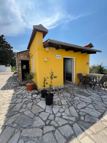 a yellow house with potted plants and a patio at Apartmani Jana in Sutomore