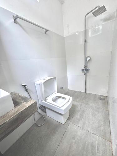 a white bathroom with a toilet and a shower at Out Of Rupeace Home Galle in Galle