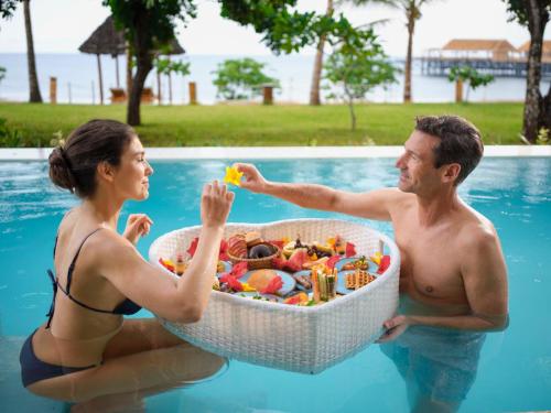 een man en een vrouw in een zwembad met een mand vol speelgoed bij Aldiana Club Zanzibar Kwanza in Kizimkazi