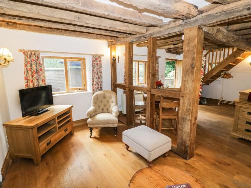 a living room with a tv and a chair at Manor Cottage in Church Stretton
