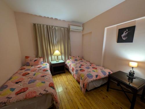 a bedroom with two beds and a table and two lamps at Tango Violin in Cairo