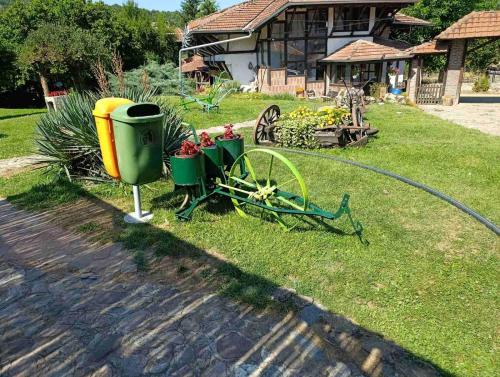 a garden with a water hose and a cart with flowers at Etno selo Srna in Kalna