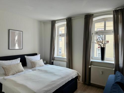 a bedroom with a bed and two windows at Ferienwohungen und Apartments Haus zum Schwan in Arnstadt