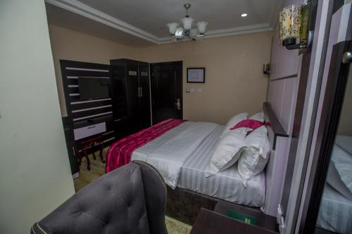 a bedroom with a bed and a desk and a chair at Doreen Grand Hotel and suites in Lagos