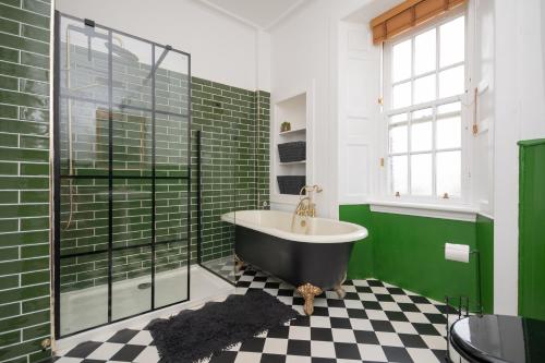 a bathroom with a tub and a green wall at Banrigh House in Stirling