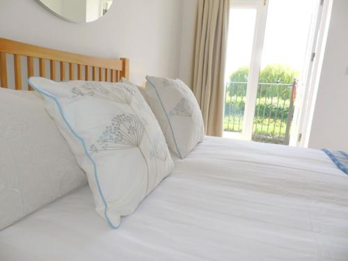 two pillows sitting on a bed with a window at River Cottage, Arundel Riverside, Just Steps from the Historic Town in Arundel