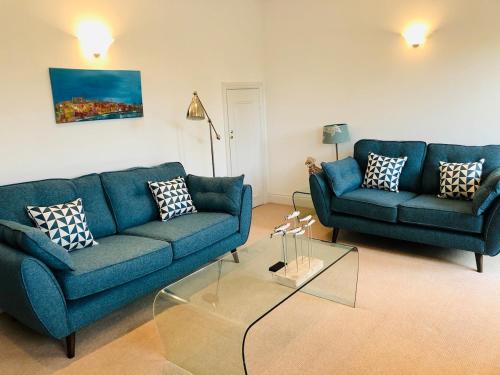 a living room with two blue couches and a table at River Cottage, Arundel Riverside, Just Steps from the Historic Town in Arundel