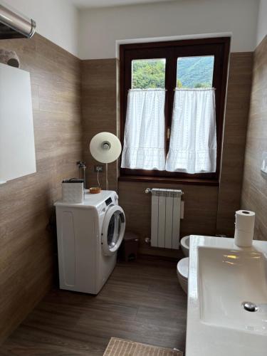 a bathroom with a toilet and a sink and a window at Civico 16 in Asso