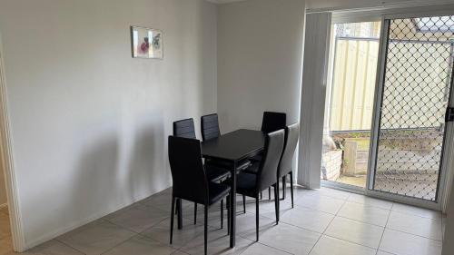 a dining room with a black table and black chairs at The Queen Nest Family House Unit 2 in Riverview