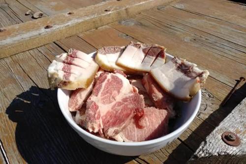 a bowl of meat and apples on a wooden table at Farmhouse Rosehip Flower Romania Brasov in Râşnov