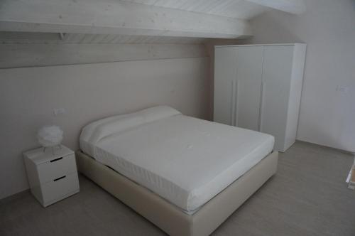 a white bedroom with a bed and a night stand at Residenza Diomedea in Vasto