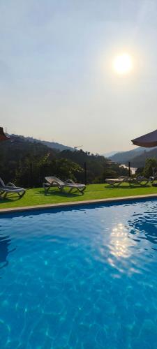 a large swimming pool with blue water in a yard at Casa da Benda in Caniçada