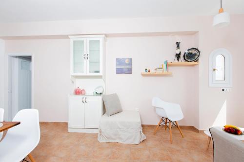 a kitchen with white cabinets and a white chair at Villa Lena in Stelida
