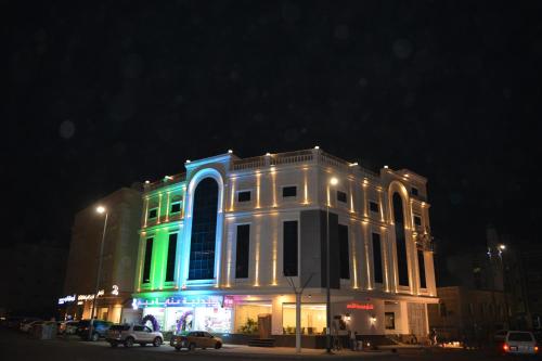 a building lit up in blue and green at night at Marina Palace Hotel in Al Madinah