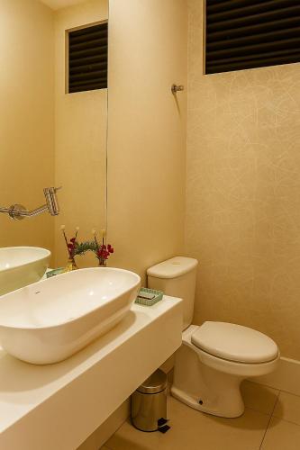 a bathroom with a white sink and a toilet at Village Prime Umarizal in Belém
