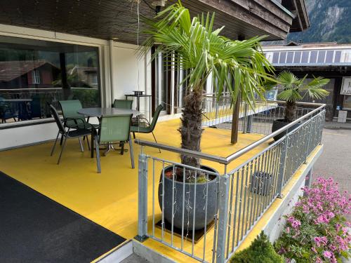 a porch with a table and a palm tree on it at Relaxen am Brienzersee mit Terrassen und Grill in Brienz