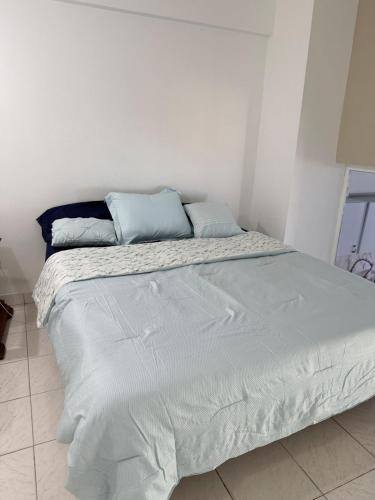 a white bed with blue pillows on top of it at Apartamento vista al mar Seaview apartment in Pampatar