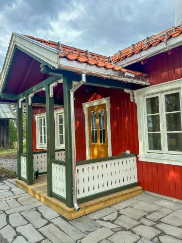 a red house with a white porch and a door at Historic Croft With Views Over Lake Mjøsa in Ottestad