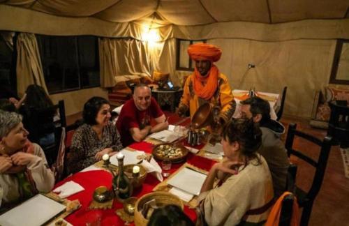 a group of people sitting around a table in a tent at Erg Chebbi Luxury Camp & Activities in Merzouga