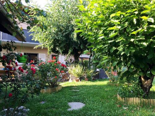 a garden with flowers and trees and a house at Au Petit Nid - Appartement douillet avec jardin privé in Albertville