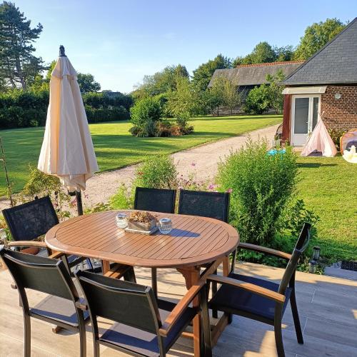 a wooden table with chairs and an umbrella at L'écurie d'antan in Hautot-Saint-Sulpice
