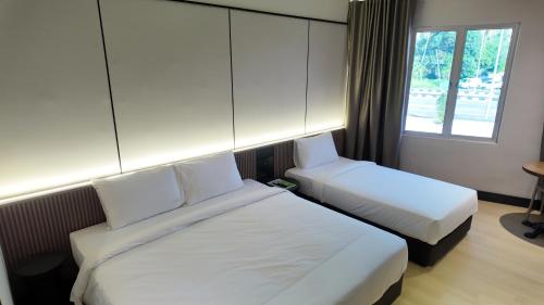 a hotel room with two beds and a window at Urban Inn, Cengal Jaya in Sungai Petani