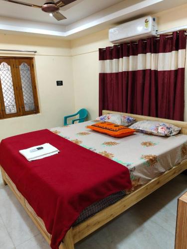 a bedroom with a bed with a red blanket on it at AMC Homestay in Tiruvannāmalai