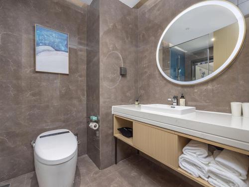 a bathroom with a toilet and a sink and a mirror at Kyriad Hotel in Tianjin