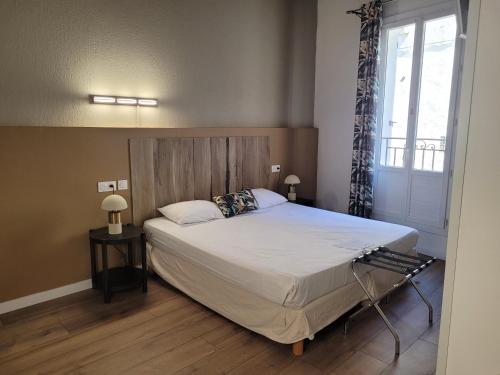 a bedroom with a bed with a wooden headboard and a window at Hôtel Boquier, Avignon Centre in Avignon