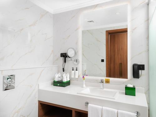 a bathroom with a sink and a mirror at Elaf Taiba Hotel in Al Madinah