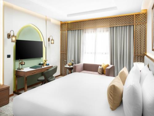 a hotel room with a large bed and a desk at Elaf Taiba Hotel in Al Madinah