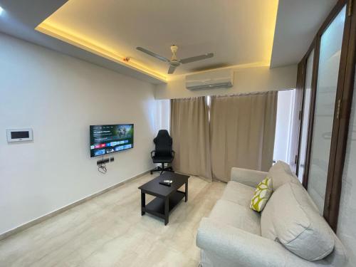 a living room with a couch and a flat screen tv at Business-Ready Apt near Jio World Centre 1BR Gym Pool WiFi in Mumbai