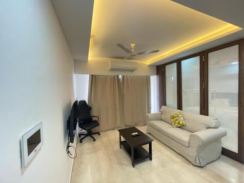 a living room with a couch and a ceiling fan at Business-Ready Apt near Jio World Centre 1BR Gym Pool WiFi in Mumbai