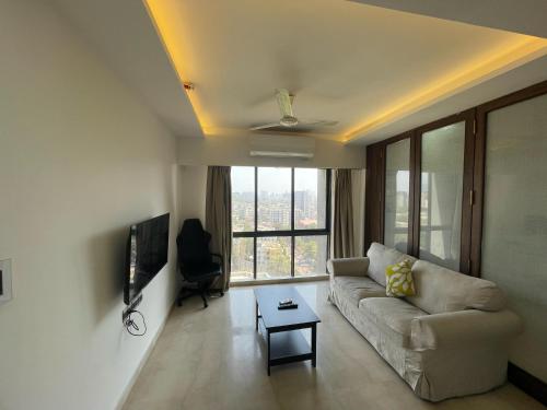 a living room with a couch and a large window at Business-Ready Apt near Jio World Centre 1BR Gym Pool WiFi in Mumbai