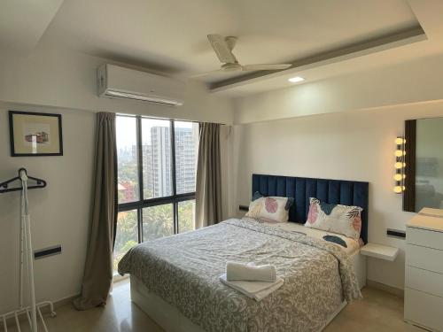 a bedroom with a bed and a large window at Business-Ready Apt near Jio World Centre 1BR Gym Pool WiFi in Mumbai
