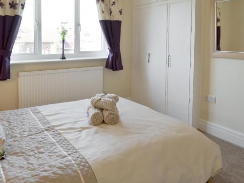 a teddy bear sitting on a bed in a bedroom at Amazing Cottage In Filey With 3 Bedrooms And Wifi in Filey