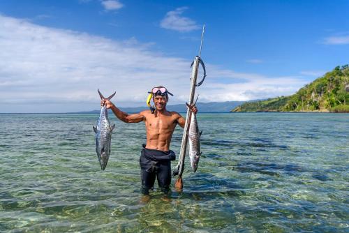 a man holding two fish in the water at The Remote Resort in Nawi