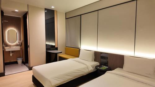 a hotel room with two beds and a mirror at Urban Inn, Cengal Jaya in Sungai Petani