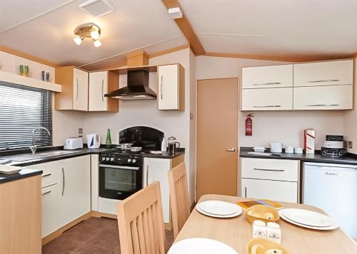 a kitchen with white cabinets and a table with chairs at Stanwix Park in Silloth
