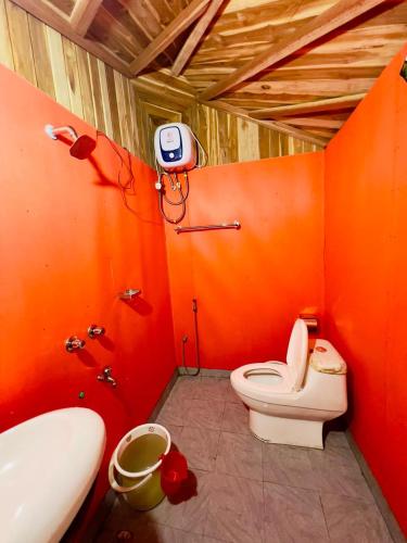 an orange bathroom with a toilet and a sink at Meghrani Eco Cottage in Māhmuam
