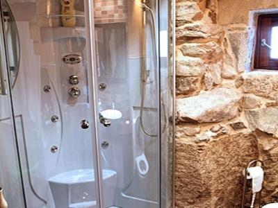 a shower in a bathroom with a stone wall at Casa Noelmar in Combarro