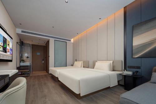 a bedroom with a large white bed and a flat screen tv at Atour Hotel Foshan Chancheng Zhangcha in Foshan