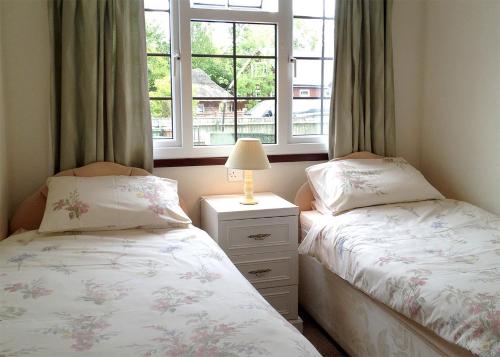 two twin beds in a room with a window at Bure-Way And Rosemere in Wroxham