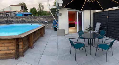 a pool with a table and chairs and an umbrella at Gîte La mésange bleue in Lohr