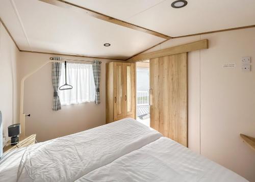 a bedroom with a white bed and a window at Riverside Holiday Village in Uphill